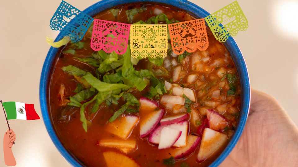 Un tazón de pozole rojo recién servido, acompañado de rábanos, lechuga y tostadas doradas.